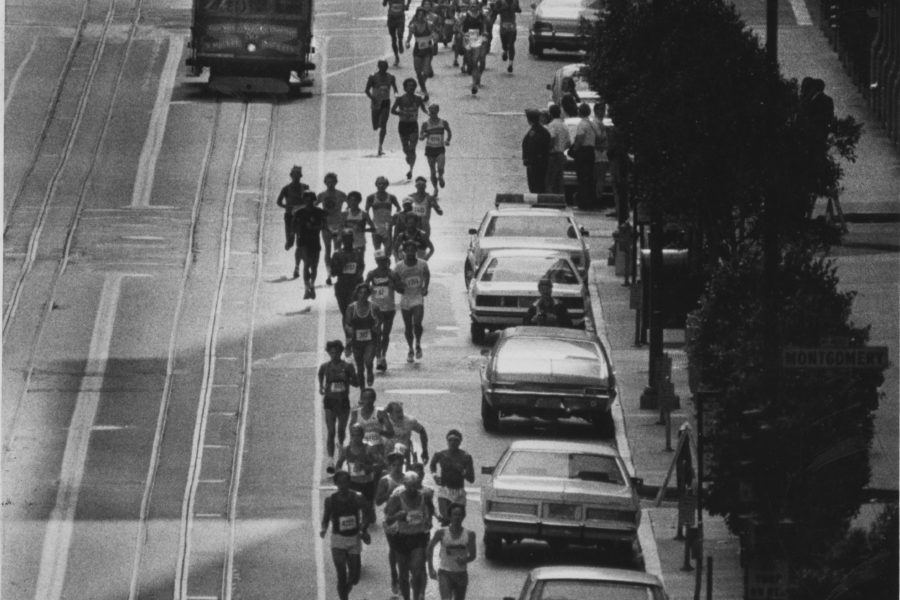 Black and white image of San Francisco Marathon Runners along side a trolley