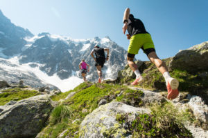 Group of people trail run with tall mountains in the background, trail running