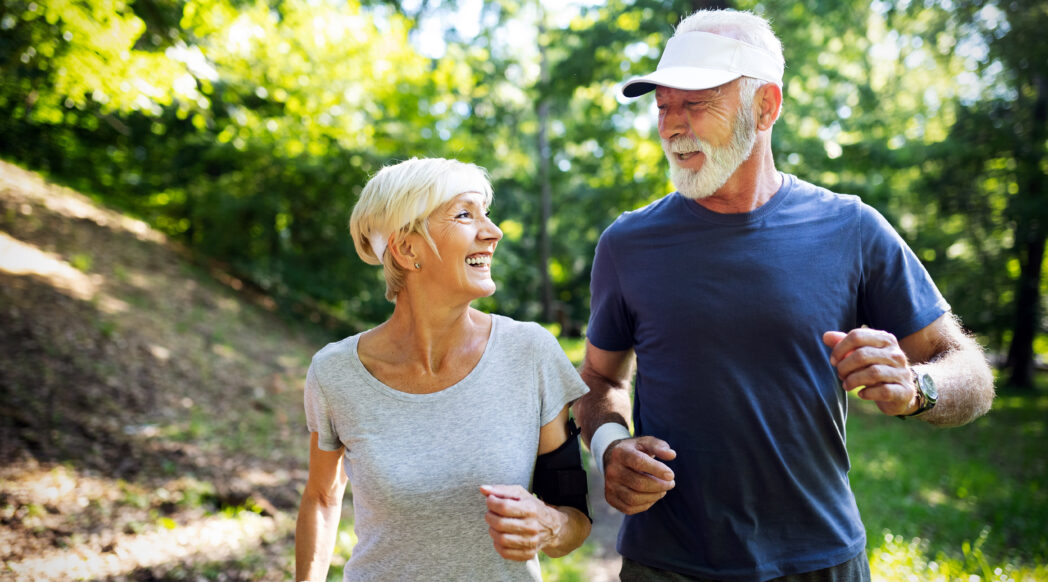An older woman and man run in a park. Choosing the right nutrition for older runners can help them stay active.