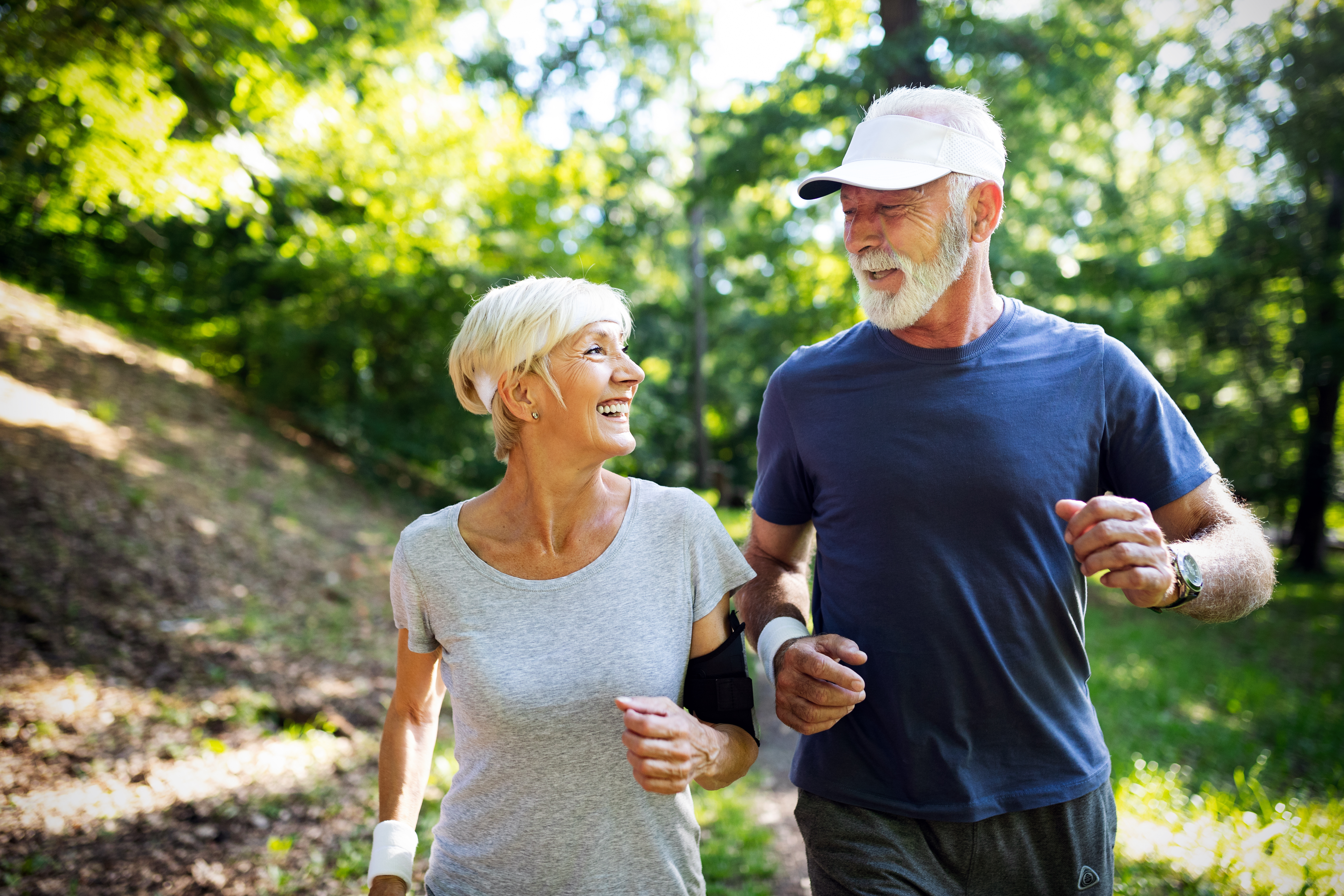 An older woman and man run in a park. Choosing the right nutrition for older runners can help them stay active.