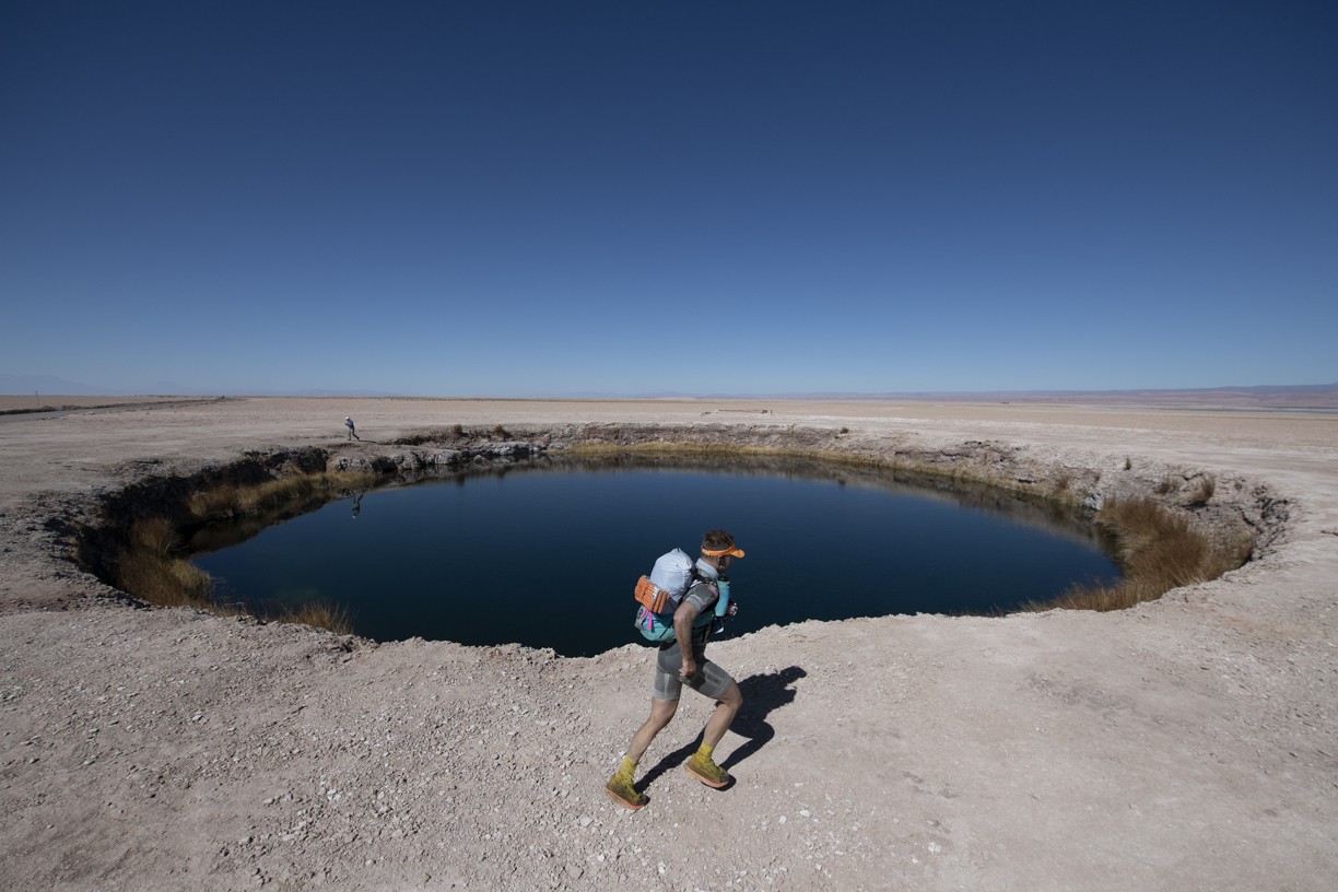 Matt Cavanaugh runs next to a water hole during the Atacama Crossing. Photo Credit: Thiago Diz/Racing the Planet