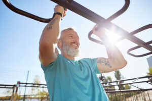 An older man does pullups at an outdoor public gym spot