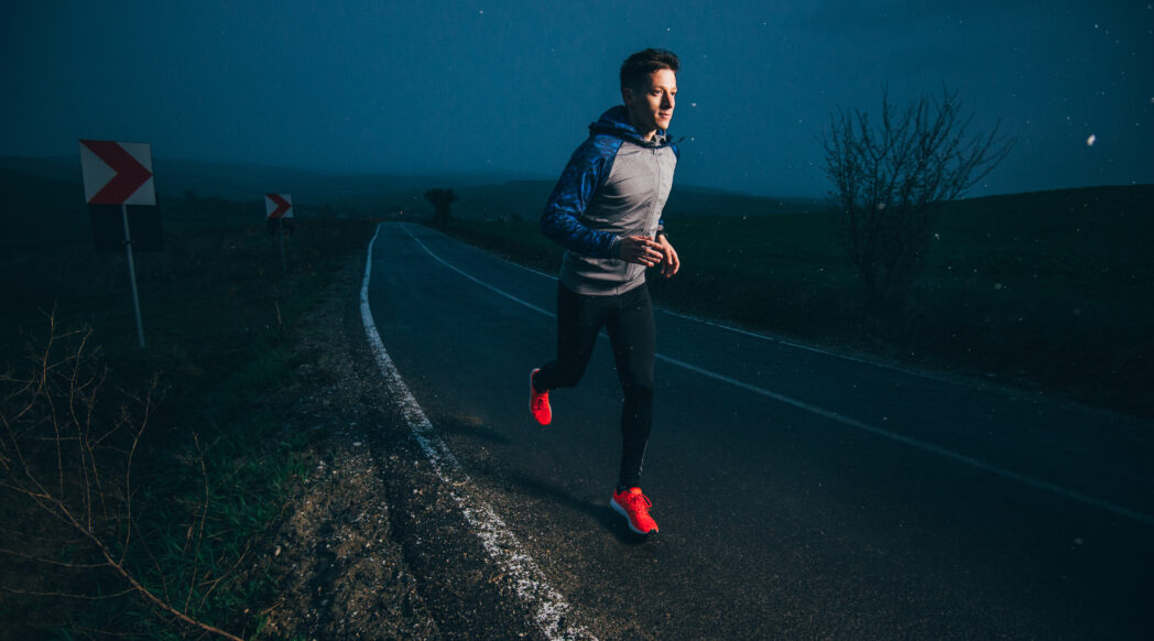 A man runs at night along a lone road, overtraining