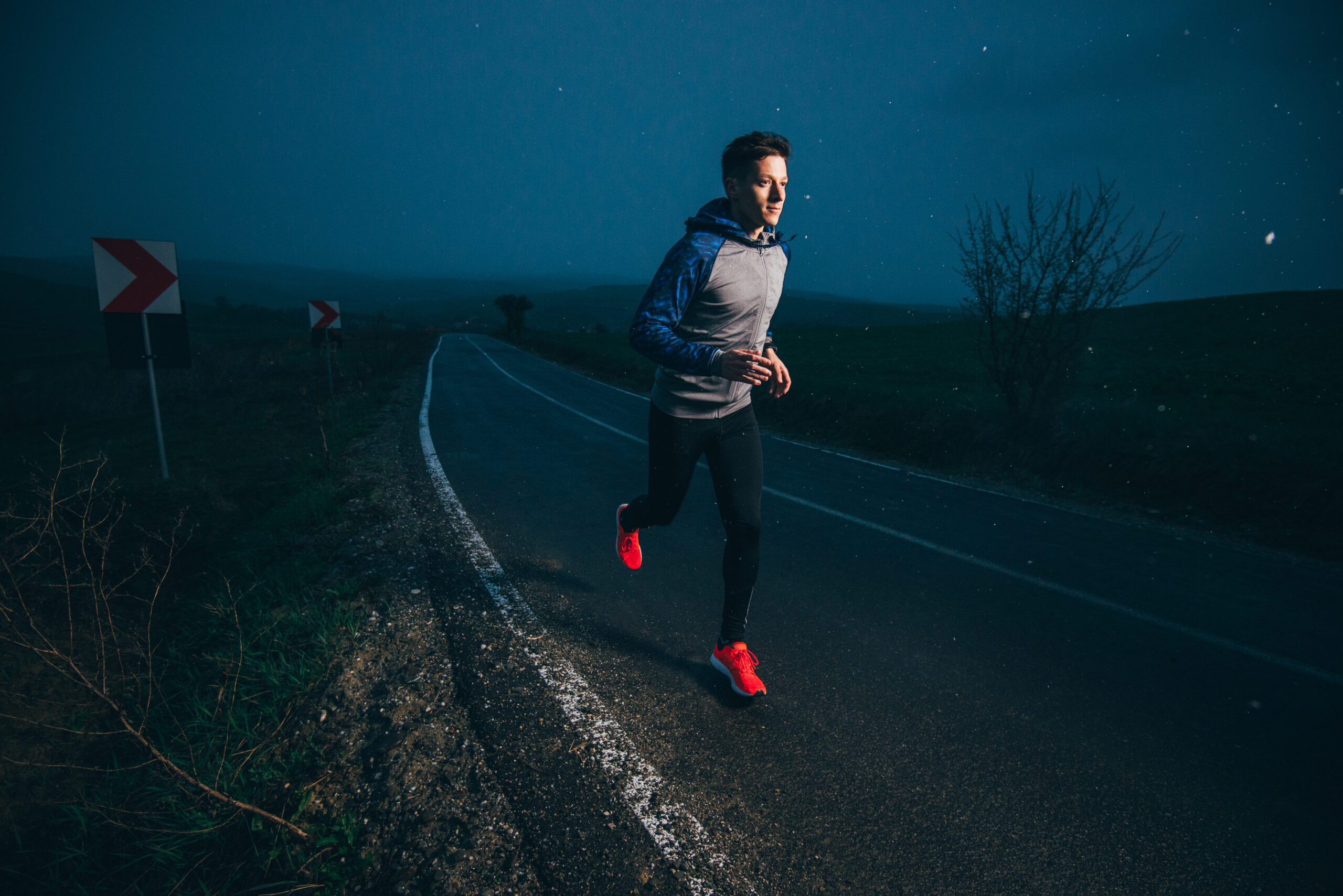 A man runs at night along a lone road, overtraining