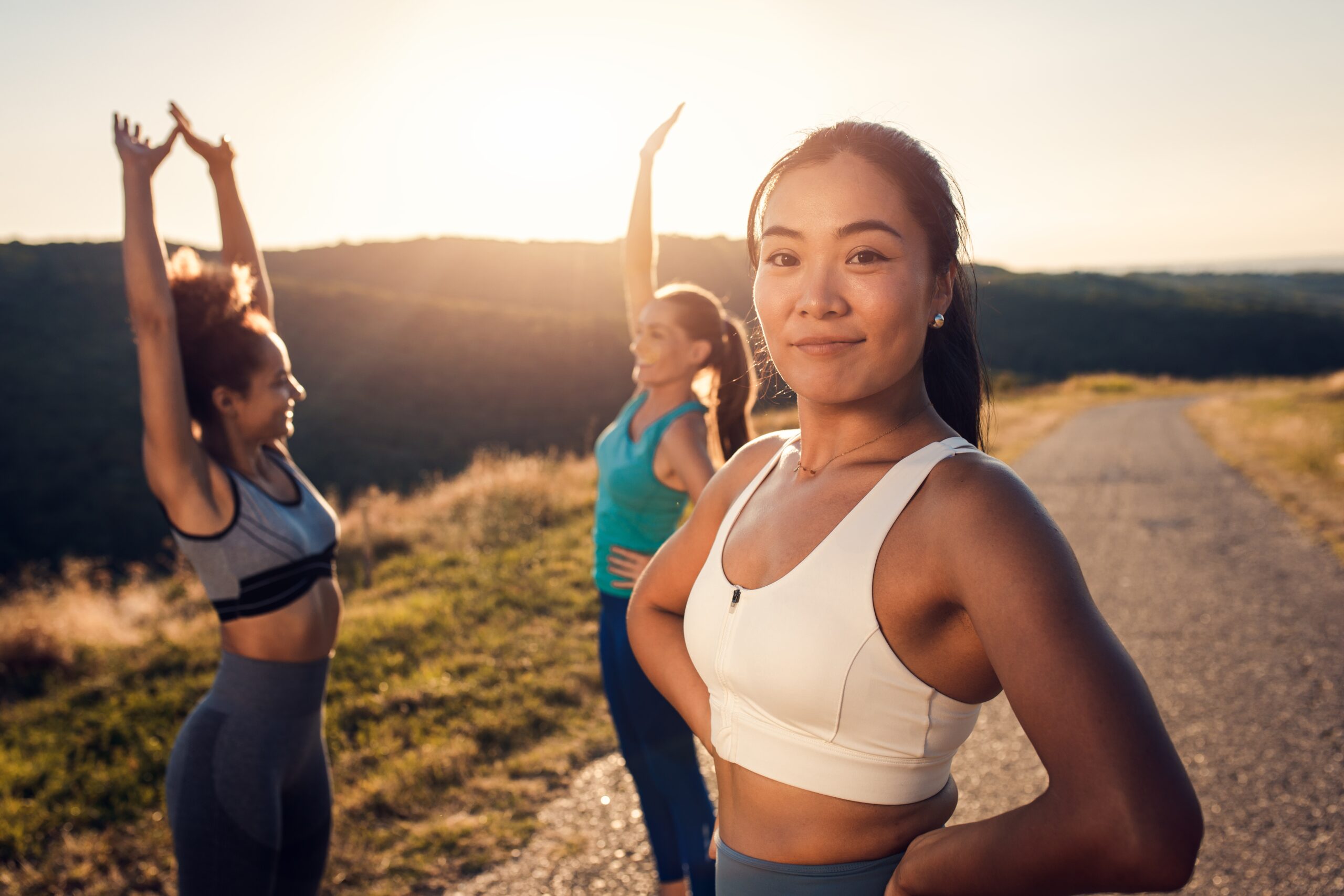 Three young women running on a trail in the late afternoon. Stick with your goals.