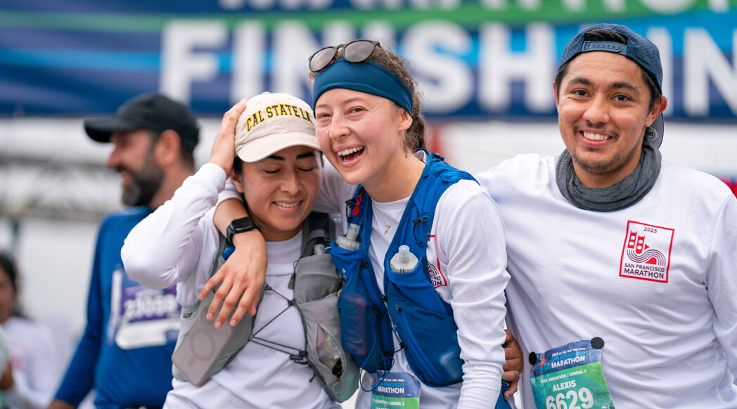 Three runners celebrate together at the finish line of the 2025 San Francisco Marathon, ready for the next challenge
