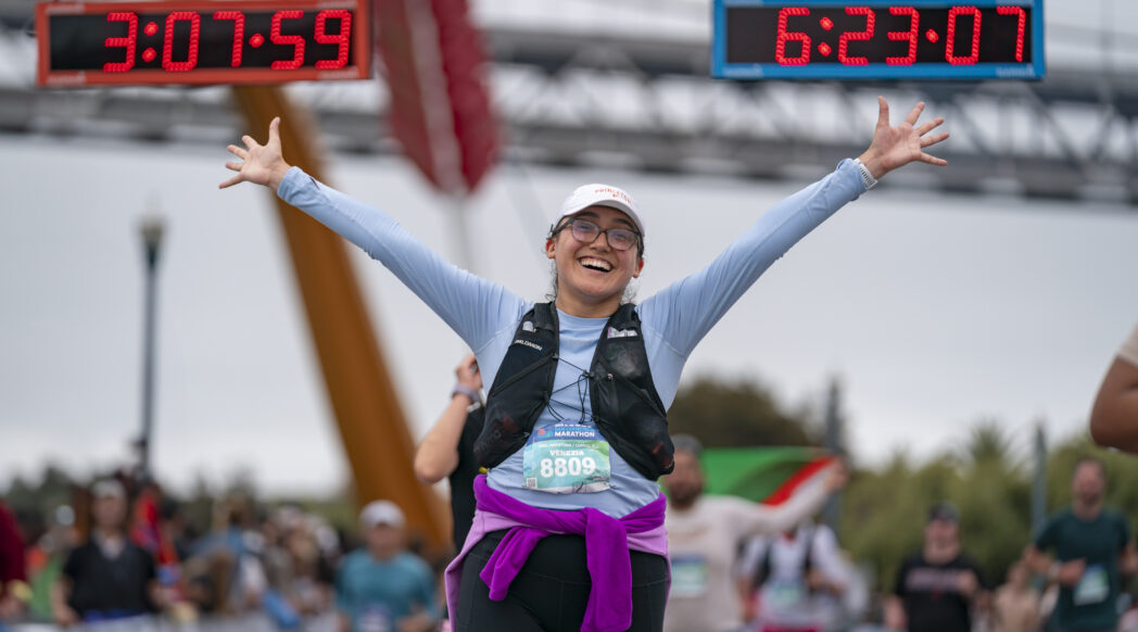 A happy runner crosses the finish line of the 2025 san francisco marathon, starting her post-race recovery journey