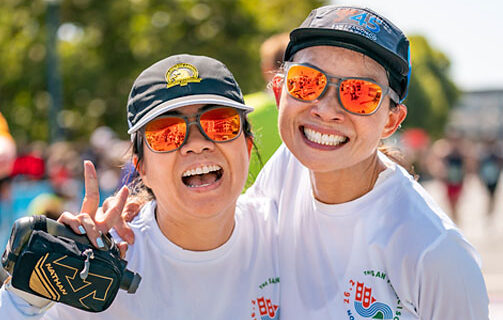 Two runners laugh as they celebrate the end of their 5k