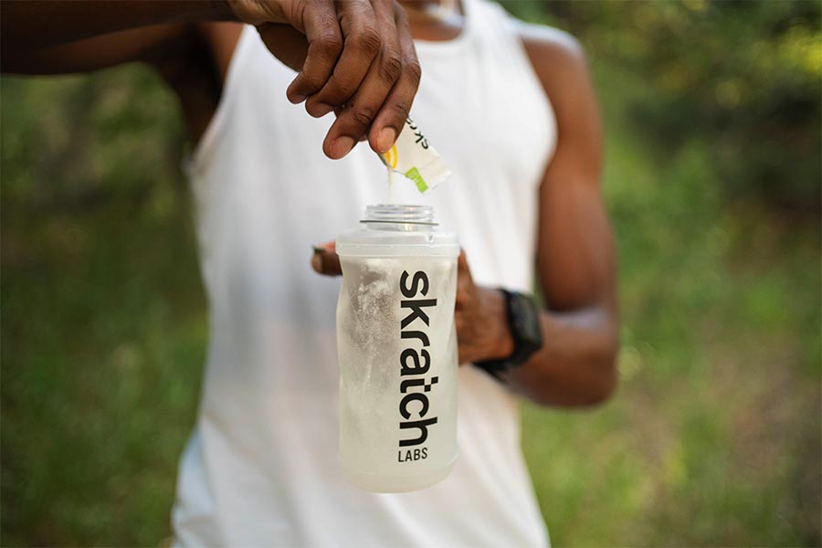 Man pouring Skratch Labs powder into a collapsible drink container