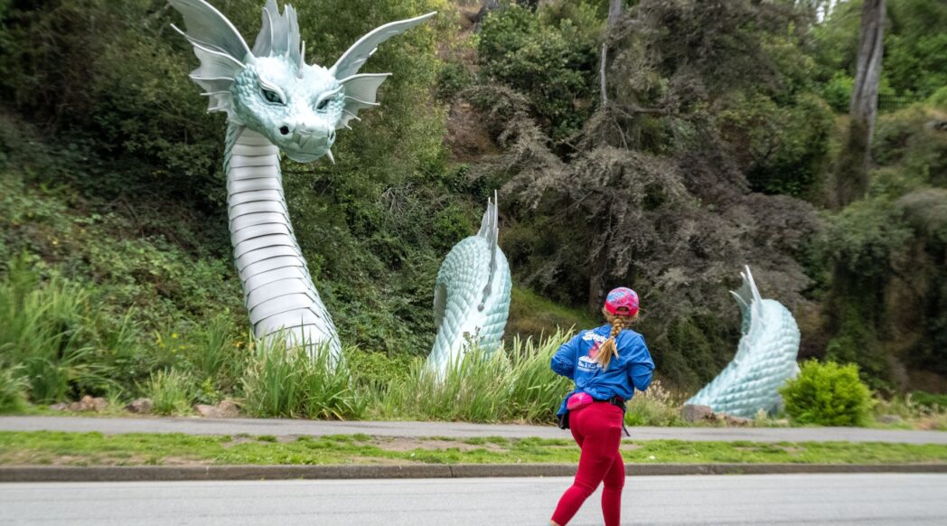 A runner runs in Golden Gate Park in front of the Naga statue