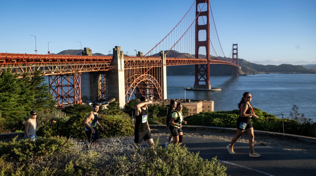 The Golden Gate Bridge, one of the Golden Gate Dozen, with small silhoutettes of runners running in front of it
