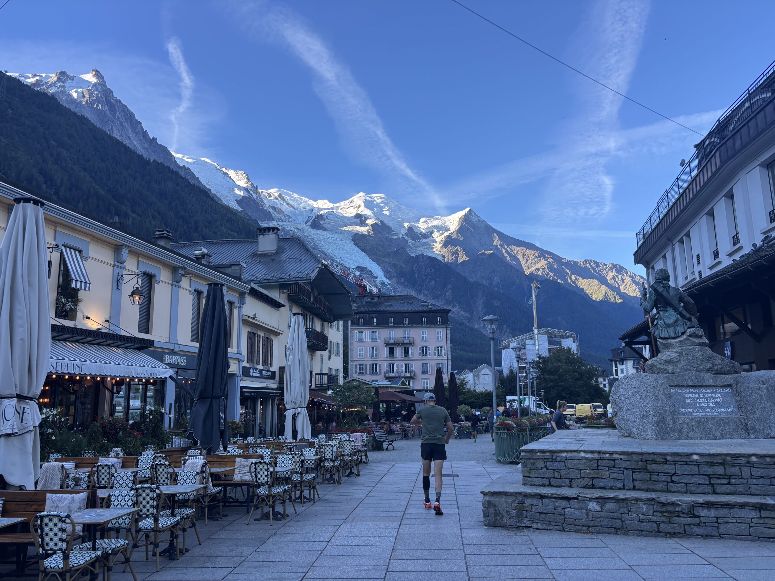A lone runner in the early morning hours runs through the centre of Chamonix during UTMB week, with Mont Blanc in the background. European running Culture.