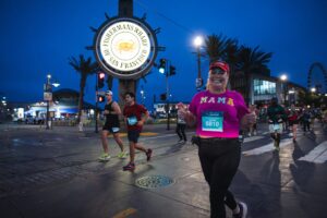 A runner runs past Fisherman's Wharf in the early morning hours with the sky deep blue and lights still on