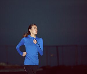 Night, runner and woman with outdoor fitness, exercise commitment and endurance training for wellness. Cardio challenge, workout and athlete with late jog for space, pace practice and determination